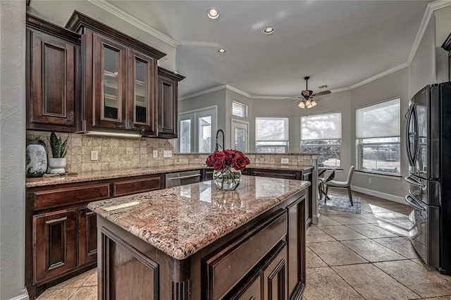 kitchen featuring black refrigerator, a center island, dark brown cabinetry, decorative backsplash, and stainless steel dishwasher