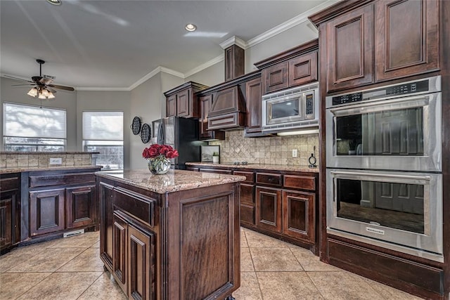 kitchen featuring appliances with stainless steel finishes, backsplash, a center island, dark brown cabinetry, and crown molding