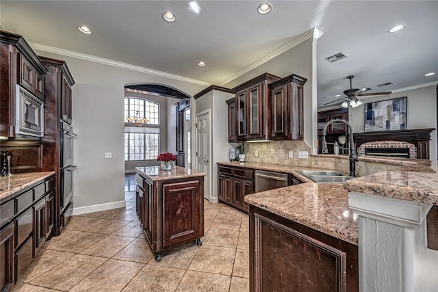 kitchen featuring stainless steel appliances, a kitchen island, sink, and dark brown cabinetry