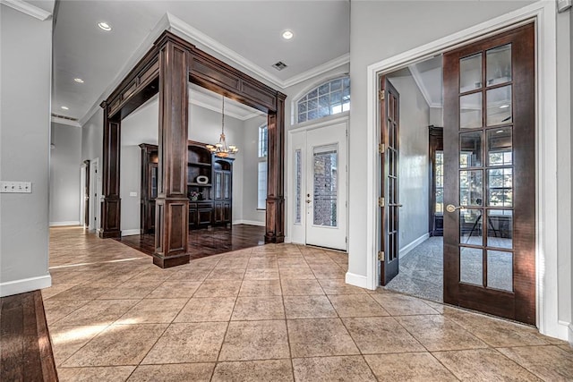 entryway with ornamental molding, tile patterned floors, a chandelier, and french doors