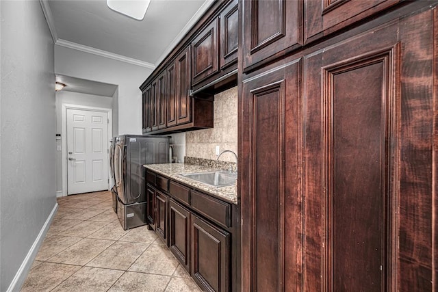 kitchen featuring washer / dryer, sink, backsplash, ornamental molding, and light stone counters