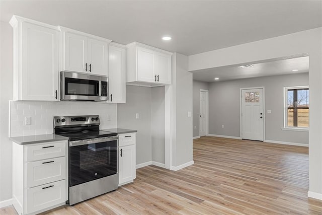 kitchen featuring stainless steel appliances, white cabinetry, backsplash, and light hardwood / wood-style floors