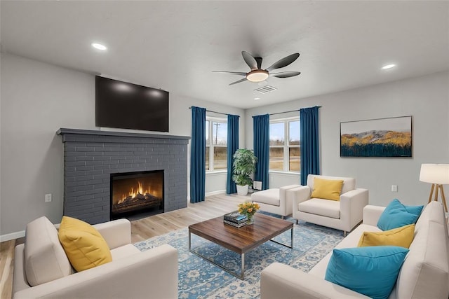 living room featuring a brick fireplace, hardwood / wood-style flooring, and ceiling fan