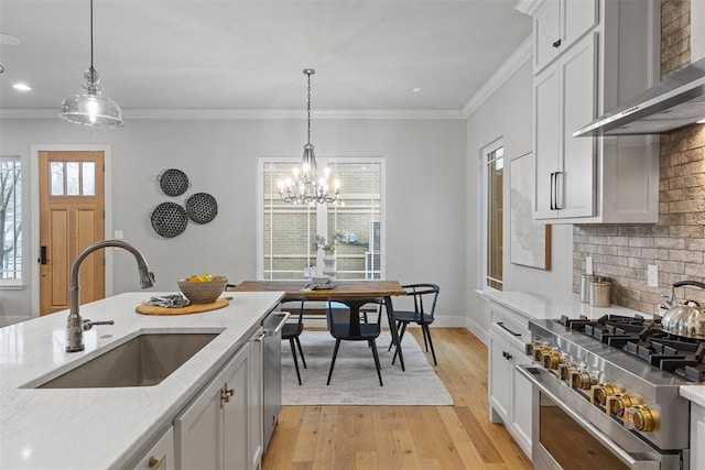 kitchen with tasteful backsplash, sink, hanging light fixtures, and wall chimney range hood