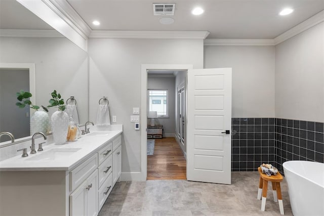 bathroom featuring crown molding, tile walls, vanity, and a tub to relax in