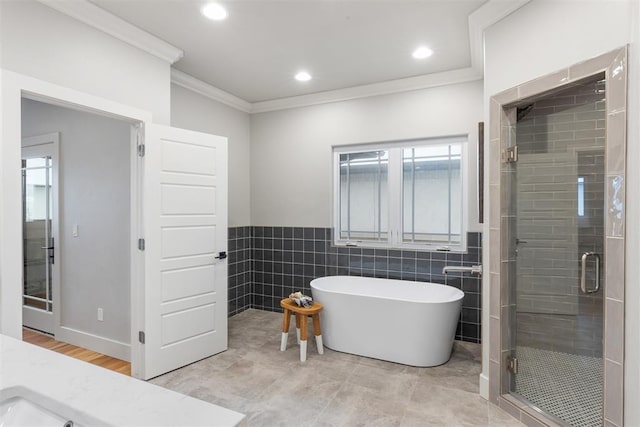 bathroom with tile walls, crown molding, and plus walk in shower