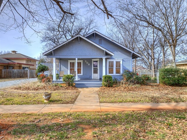 bungalow-style house featuring covered porch and fence
