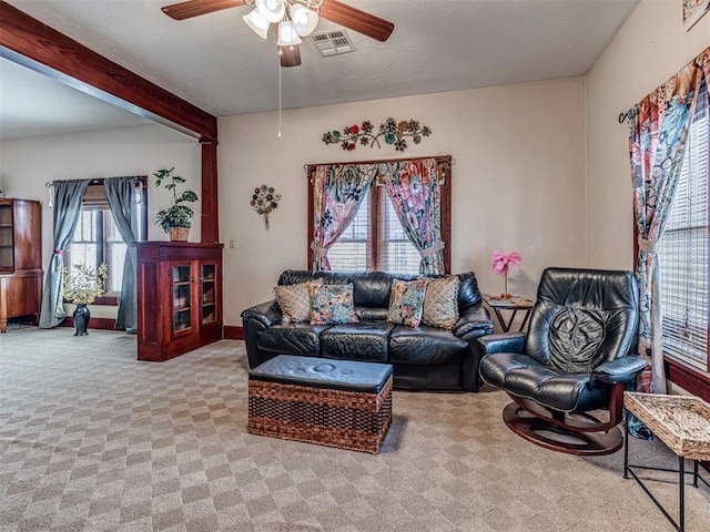 living room featuring beamed ceiling, ceiling fan, and light carpet