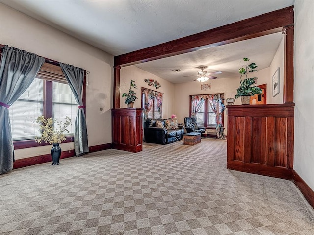 carpeted living room with beamed ceiling, a textured ceiling, and ceiling fan