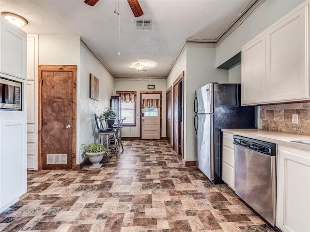 kitchen with tasteful backsplash, ornamental molding, appliances with stainless steel finishes, ceiling fan, and white cabinets