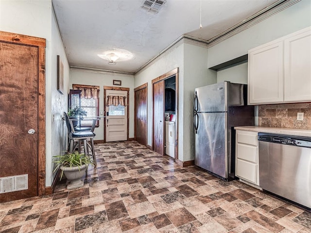 kitchen with backsplash, ornamental molding, stainless steel appliances, and white cabinets