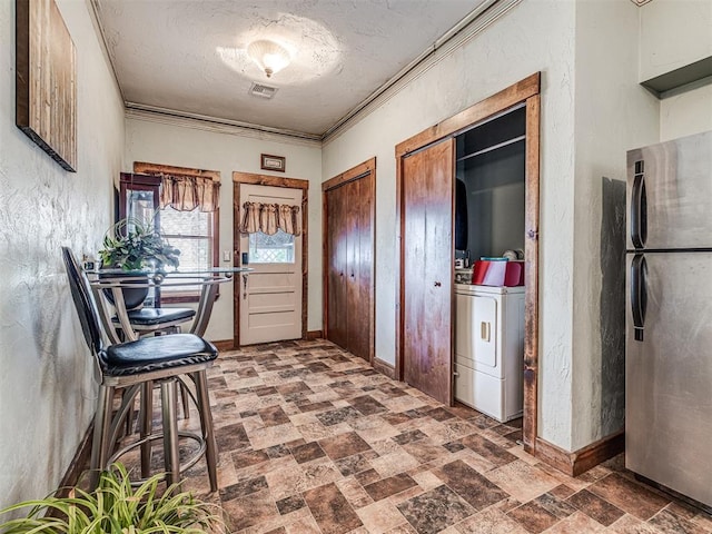 interior space featuring washer and clothes dryer, ornamental molding, and a textured ceiling