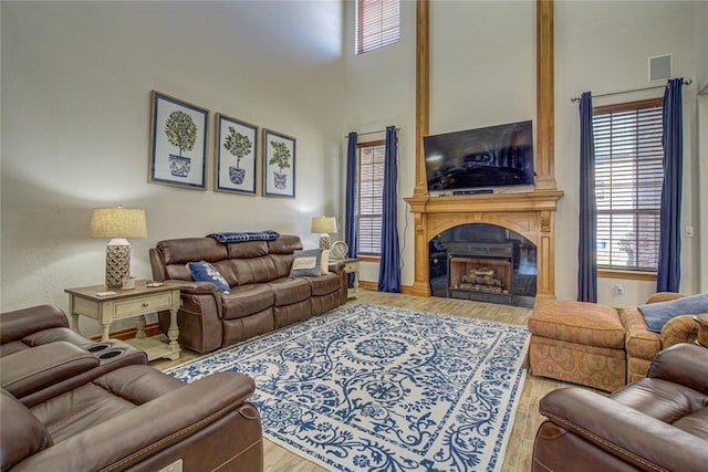 living room featuring a fireplace, wood-type flooring, and a high ceiling