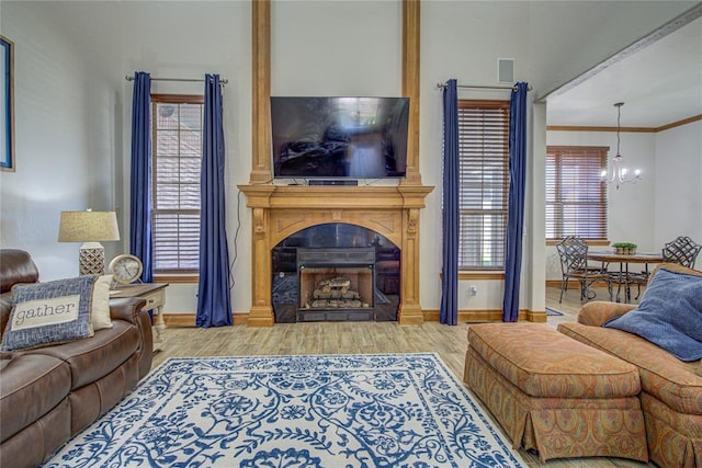 living room featuring hardwood / wood-style floors, crown molding, a fireplace, and a chandelier