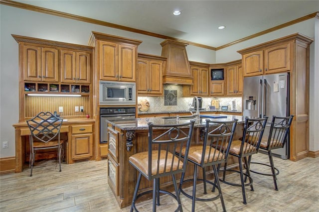 kitchen with premium range hood, a kitchen bar, dark stone counters, a kitchen island with sink, and stainless steel appliances