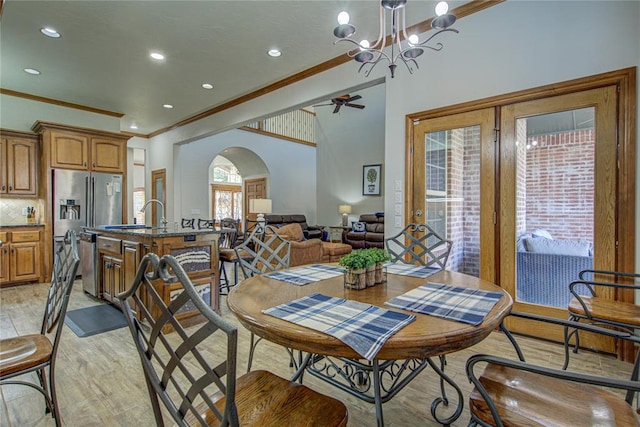 dining space featuring crown molding, sink, ceiling fan with notable chandelier, and light hardwood / wood-style flooring