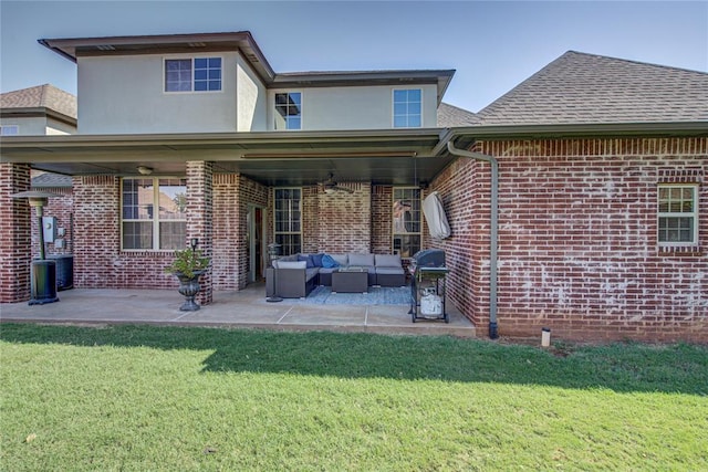 rear view of property with ceiling fan, a yard, an outdoor living space, and a patio