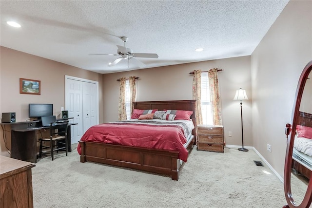 carpeted bedroom with ceiling fan, a closet, and a textured ceiling