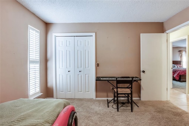 bedroom featuring light colored carpet, a closet, and a textured ceiling