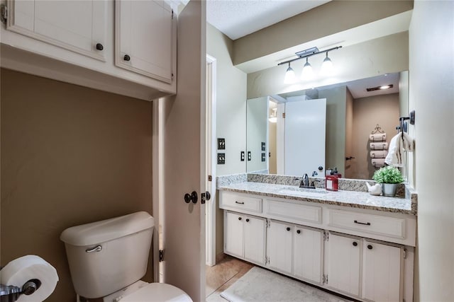 bathroom featuring vanity, tile patterned floors, and toilet