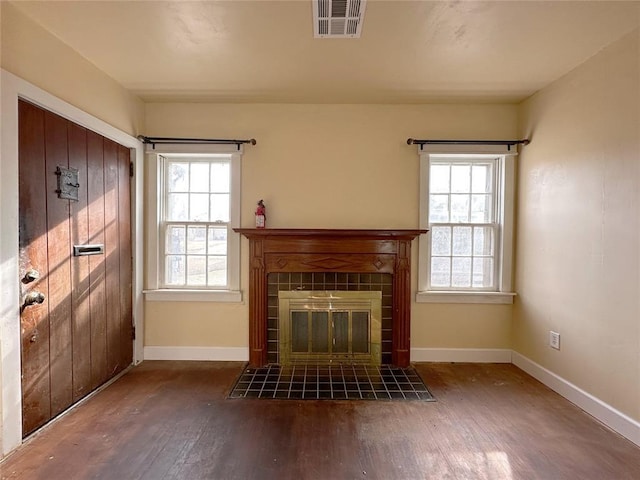 unfurnished living room with a fireplace, a healthy amount of sunlight, and dark hardwood / wood-style floors