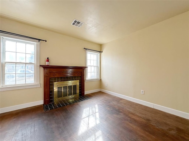 unfurnished living room featuring dark wood-type flooring and a tile fireplace