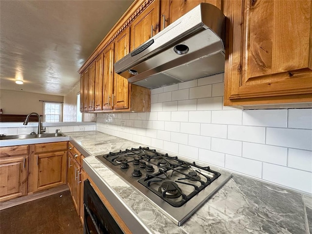 kitchen with dark hardwood / wood-style floors, black oven, stainless steel gas stovetop, tasteful backsplash, and sink