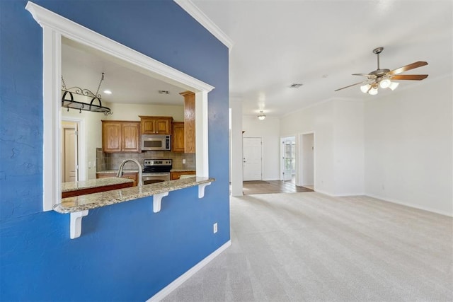 kitchen featuring a breakfast bar, ornamental molding, light colored carpet, stainless steel appliances, and backsplash