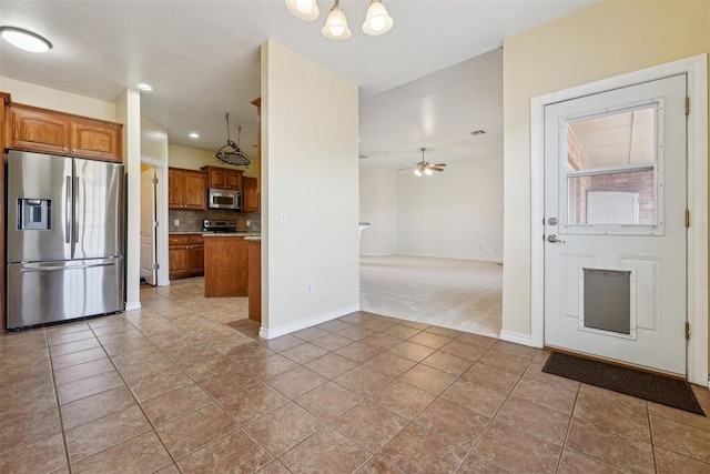 kitchen featuring decorative backsplash, stainless steel appliances, hanging light fixtures, and light tile patterned floors