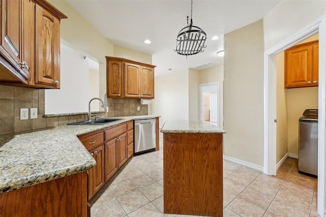 kitchen featuring a kitchen island, dishwasher, washer / dryer, sink, and hanging light fixtures