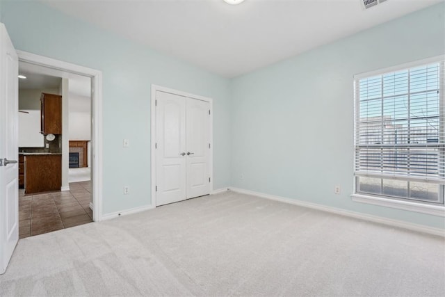 unfurnished bedroom with light carpet and a closet