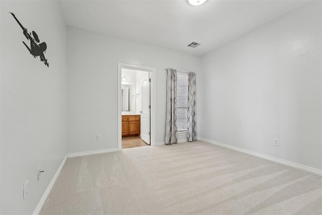 unfurnished bedroom featuring connected bathroom and light carpet