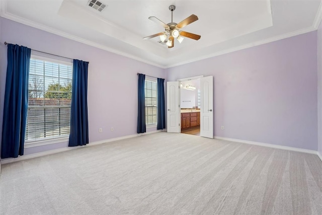 unfurnished bedroom with ornamental molding, light colored carpet, ceiling fan, and a tray ceiling