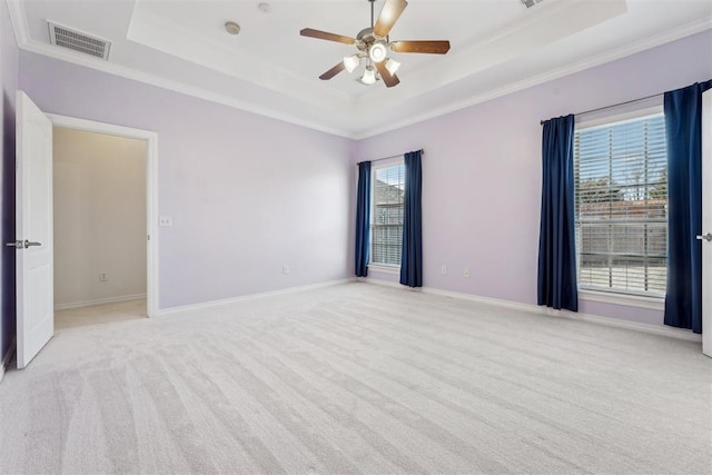 empty room featuring ornamental molding, light colored carpet, and a raised ceiling