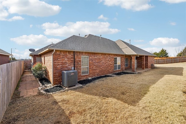 rear view of house featuring cooling unit, a lawn, and a patio