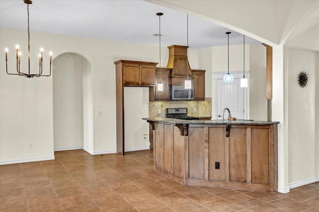 kitchen featuring pendant lighting, a kitchen bar, backsplash, and stove