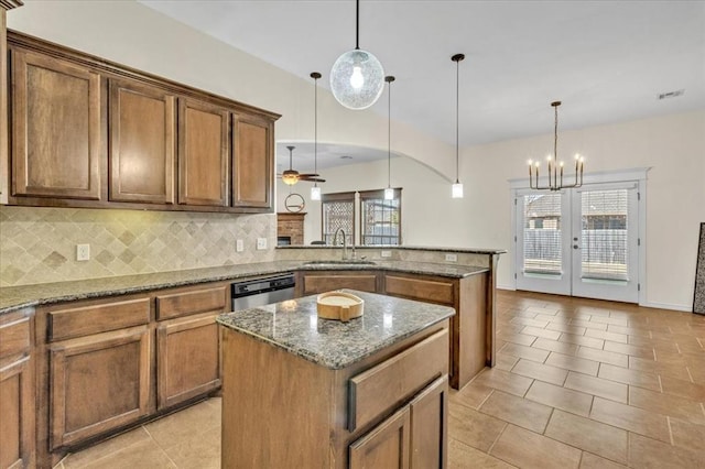 kitchen featuring stone countertops, dishwasher, sink, hanging light fixtures, and a center island