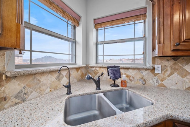 kitchen featuring tasteful backsplash, sink, a mountain view, and light stone countertops