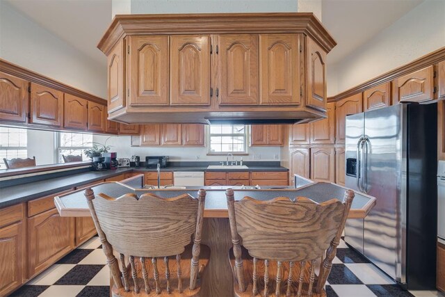 414315 E 1080th Rd, Checotah, OK 74426 - kitchen with stainless steel refrigerator with ice dispenser, tile patterned floors, dark countertops, brown cabinets, and white dishwasher