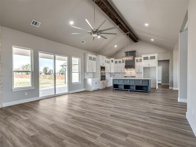 unfurnished living room featuring sink, hardwood / wood-style flooring, ceiling fan, high vaulted ceiling, and beamed ceiling