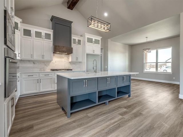 kitchen featuring pendant lighting, a kitchen island with sink, sink, and white cabinets