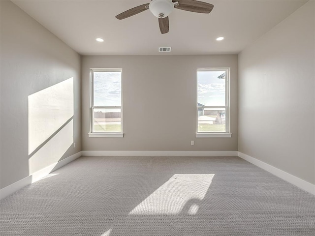 empty room featuring a wealth of natural light, light colored carpet, and ceiling fan