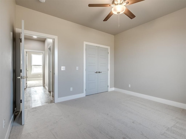 unfurnished bedroom featuring light carpet, ceiling fan, and a closet