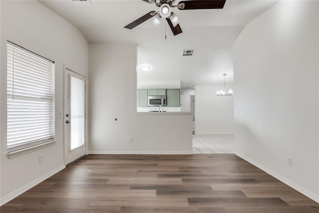 unfurnished living room featuring ceiling fan with notable chandelier and hardwood / wood-style floors