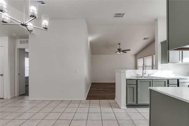 kitchen featuring lofted ceiling, light tile patterned floors, sink, hanging light fixtures, and ceiling fan with notable chandelier