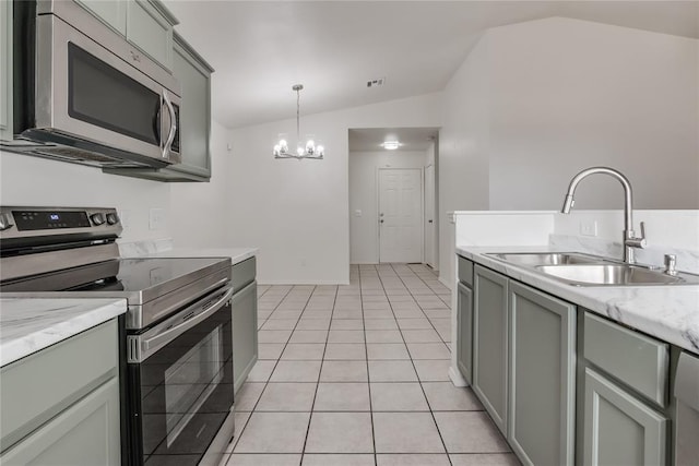 kitchen featuring light tile patterned flooring, lofted ceiling, sink, pendant lighting, and stainless steel appliances