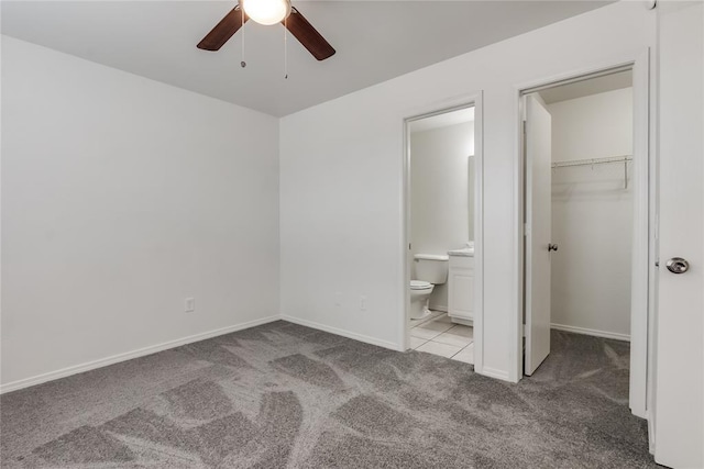 unfurnished bedroom featuring a walk in closet, light colored carpet, ensuite bath, and a closet