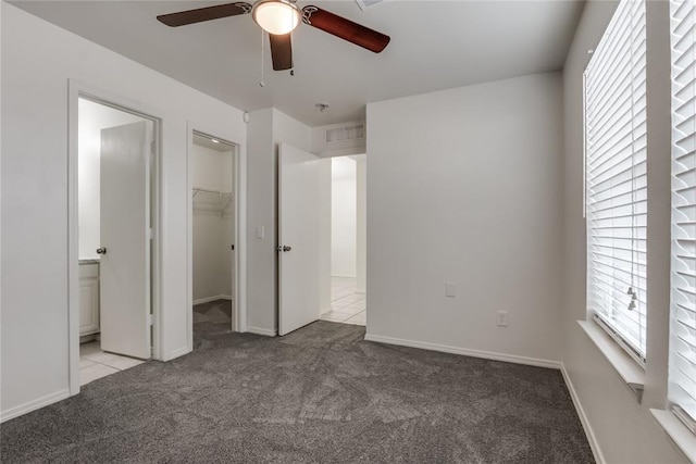 unfurnished bedroom featuring a spacious closet, light carpet, ceiling fan, and a closet