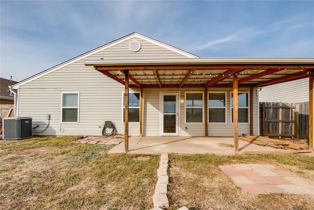 rear view of property featuring central AC unit, a lawn, and a patio