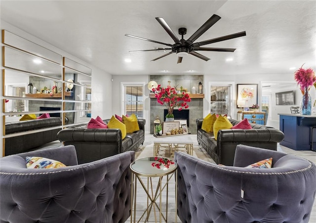 living room featuring a large fireplace and ceiling fan